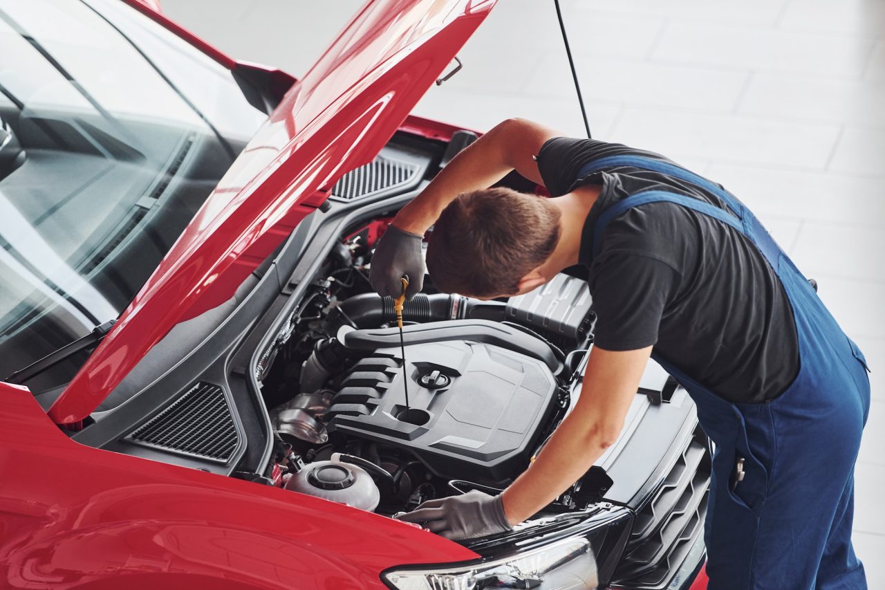 Start 26 top view of male worker in uniform that repairs red automobile